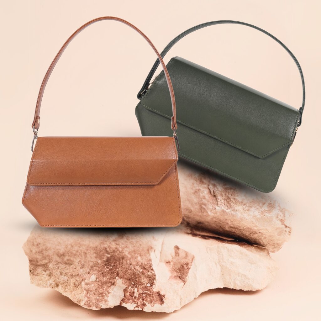 Two bags on a rock: a brown shoulder bag and a green bag, showcasing their textures and colors in natural surroundings.
